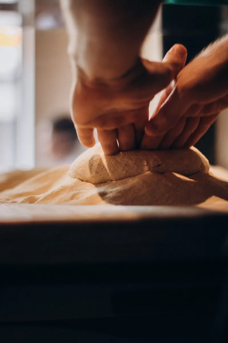 Des mains pressent une pâte sur un plan de travail fariné